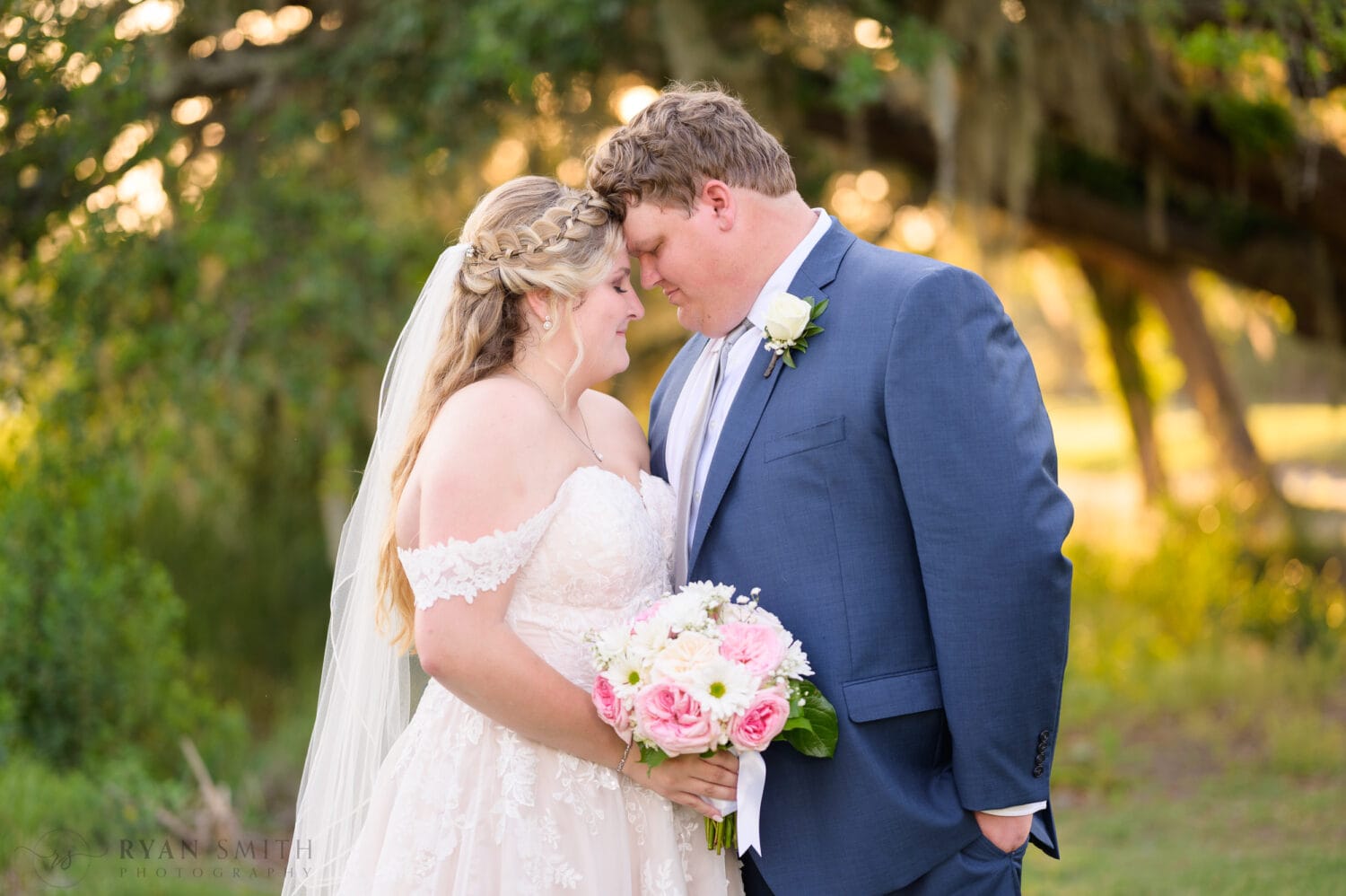 Touching foreheads backlit by the bokeh of the light filtering through the oaks - Pawleys Plantation