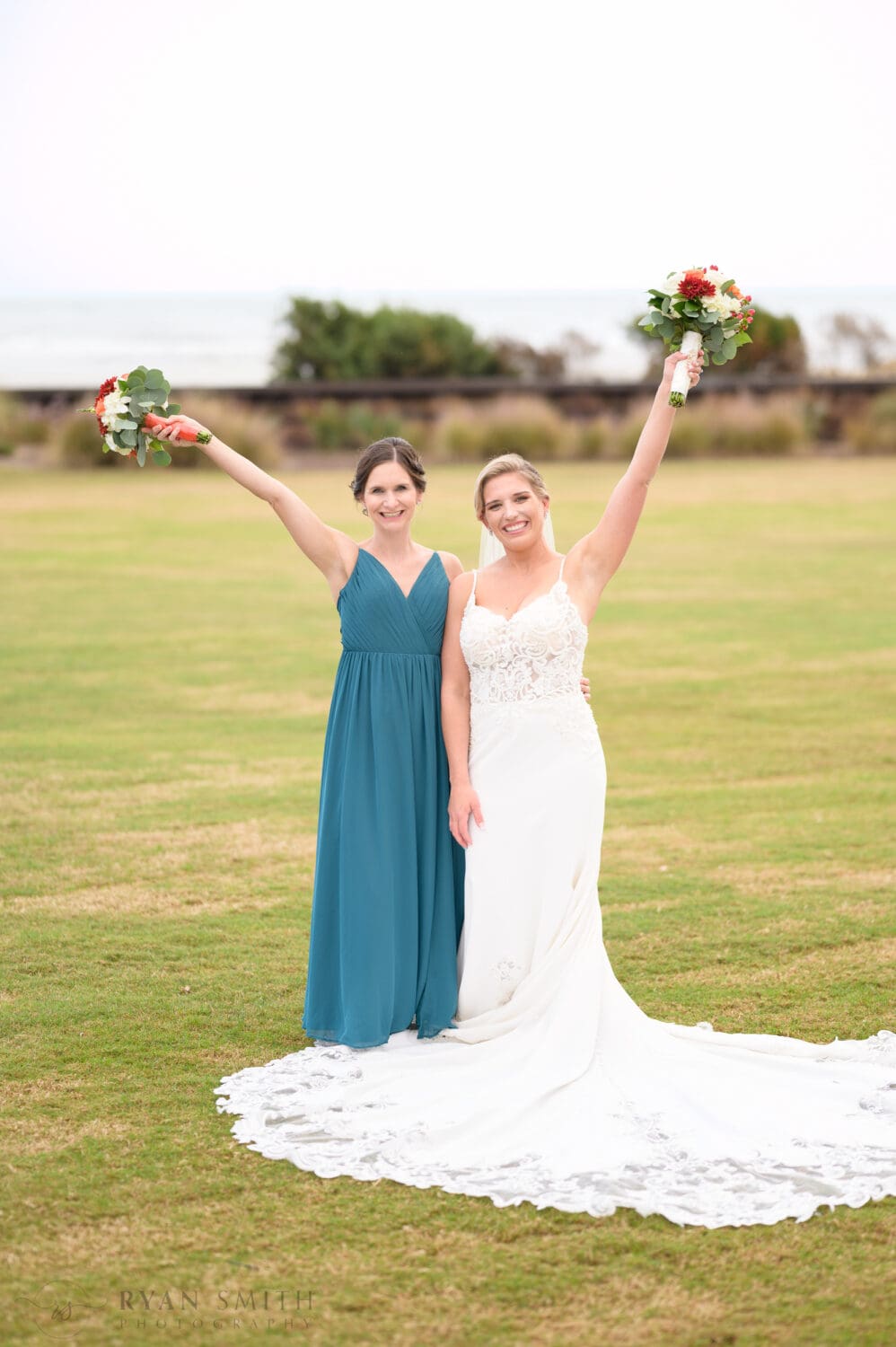 Bride and bridesmaid holding flowers in the air - Dunes Golf & Beach Club
