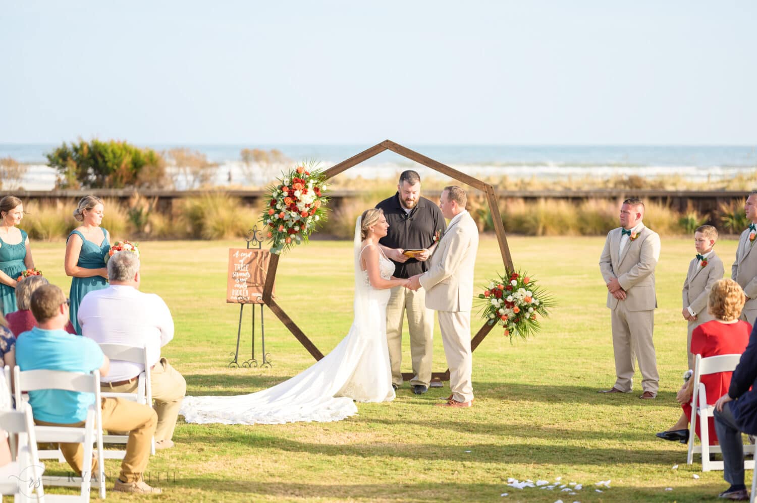 Bride and groom holding hands during the ceremony - Dunes Golf & Beach Club