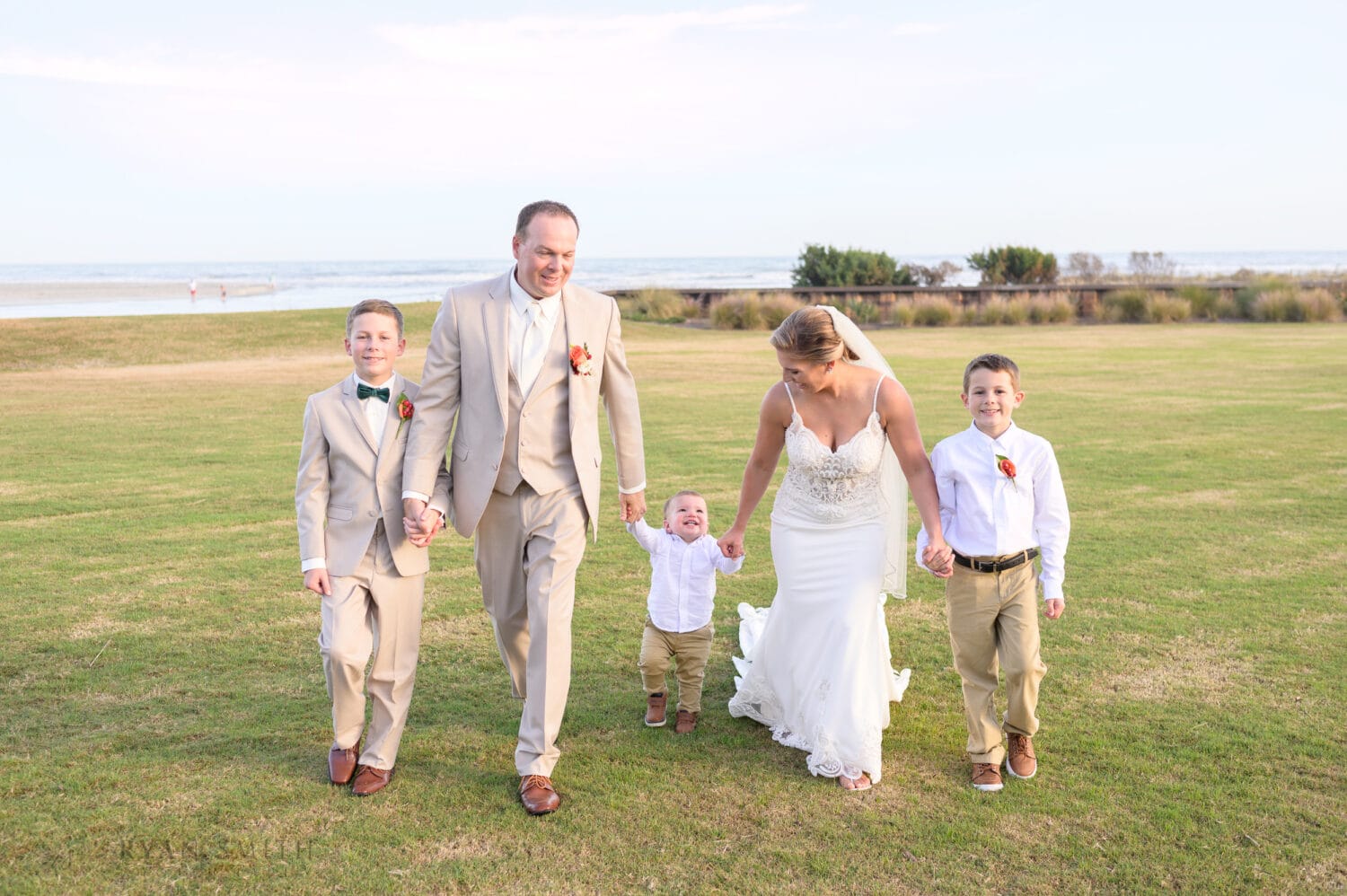 Bride and groom walking together with their kids - Dunes Golf & Beach Club