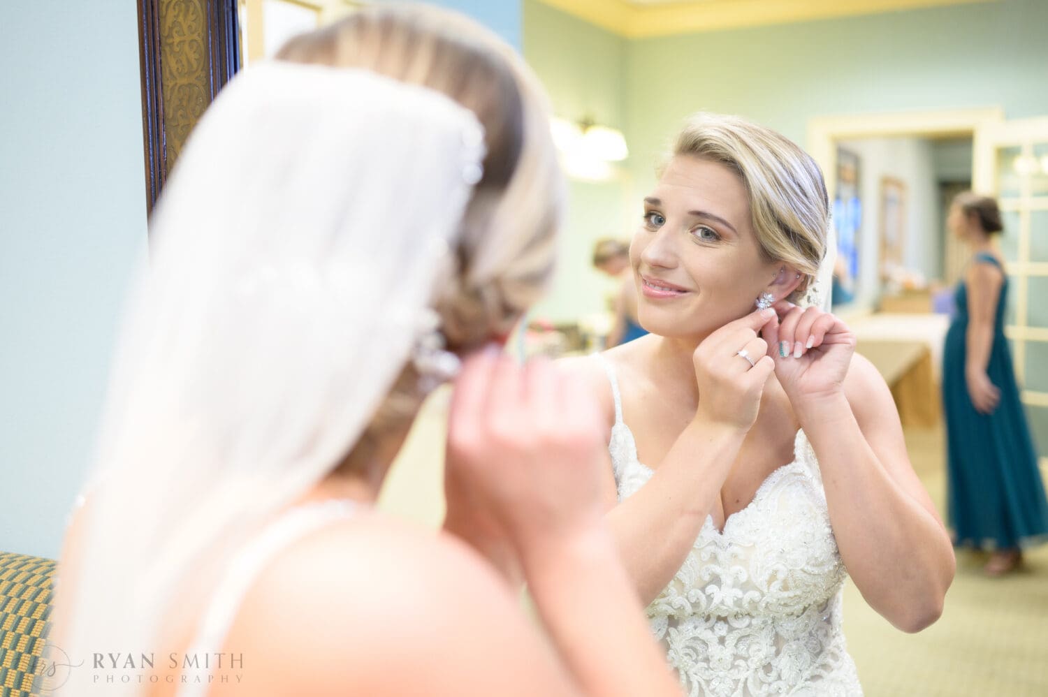Bride putting on earrings in the mirror - Dunes Golf & Beach Club