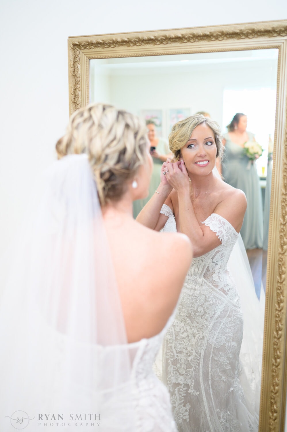 Bride putting on her earrings in the mirror - The Village House at Litchfield