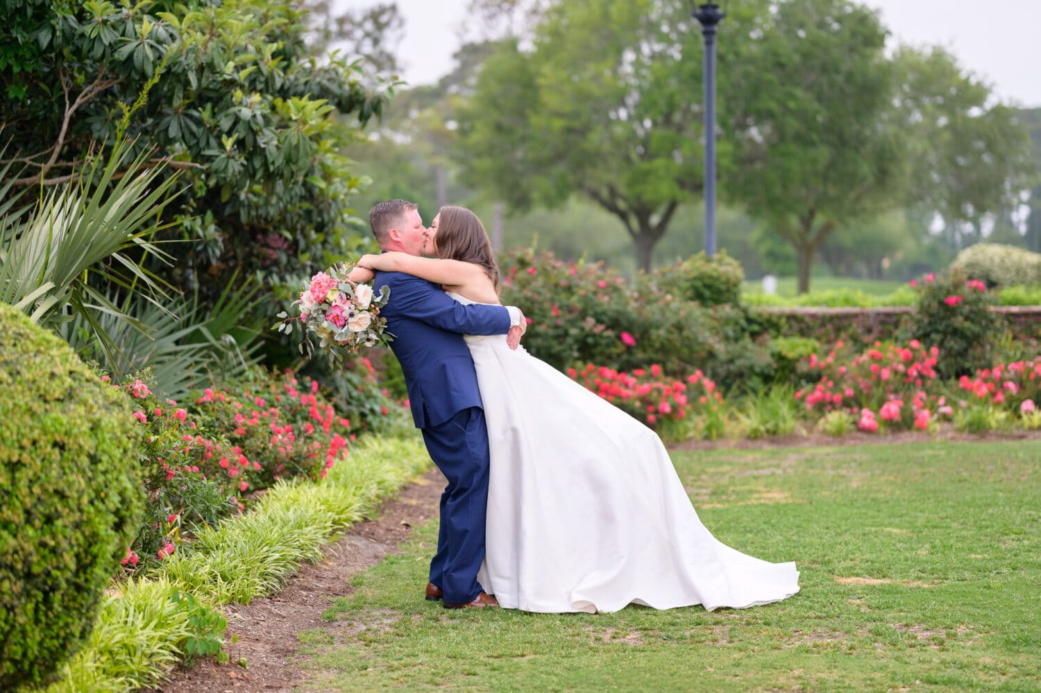 Lifting bride up for a kiss by the flowers - Pine Lakes Country Club