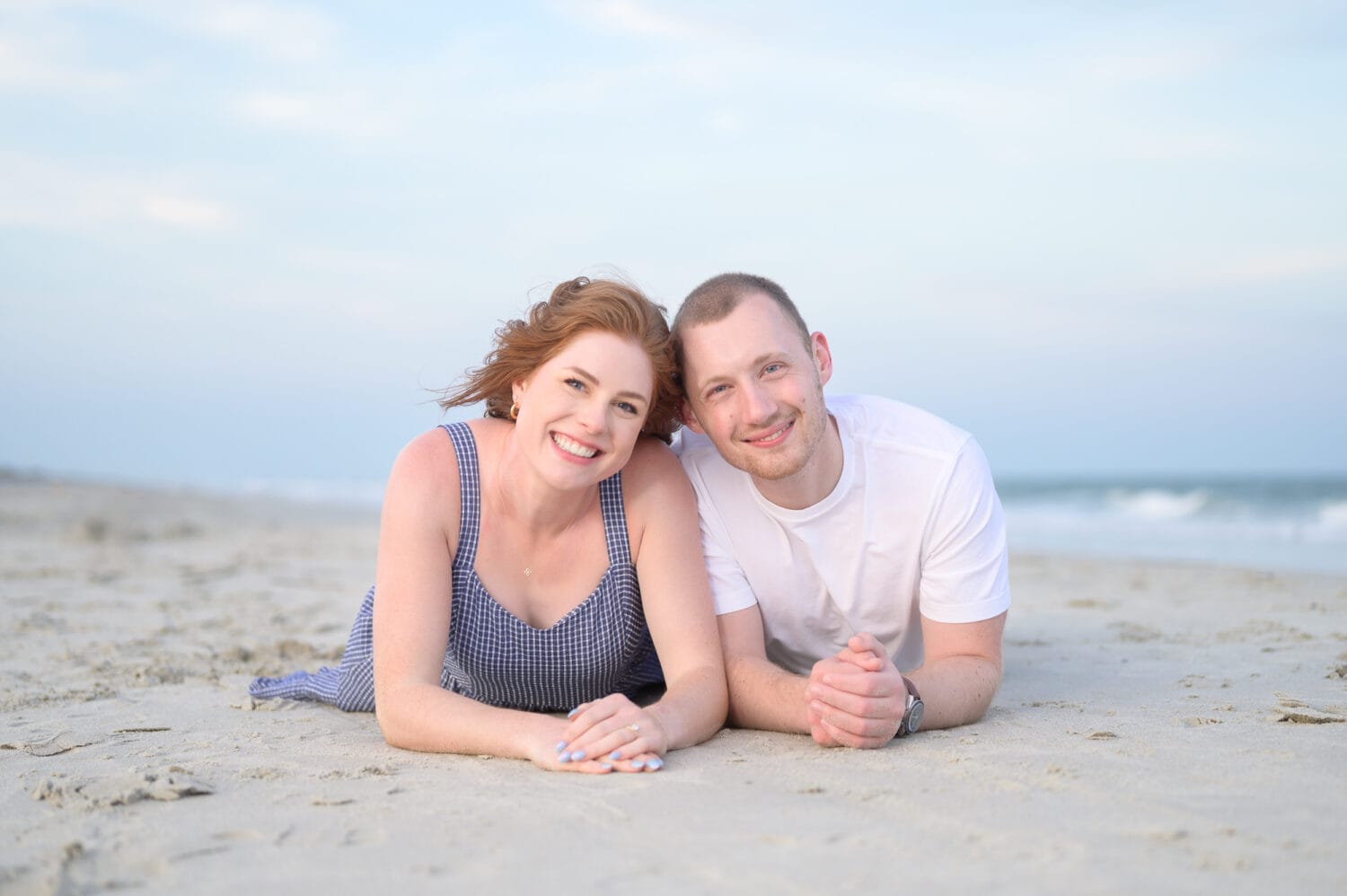 Engagement portrait laying on the beach together - Huntington Beach State Park