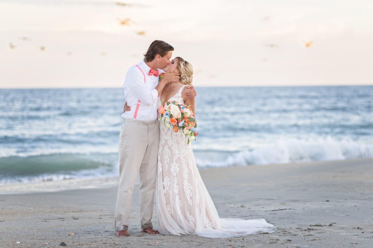 Bride and groom kissing on a beautiful evening by the ocean -