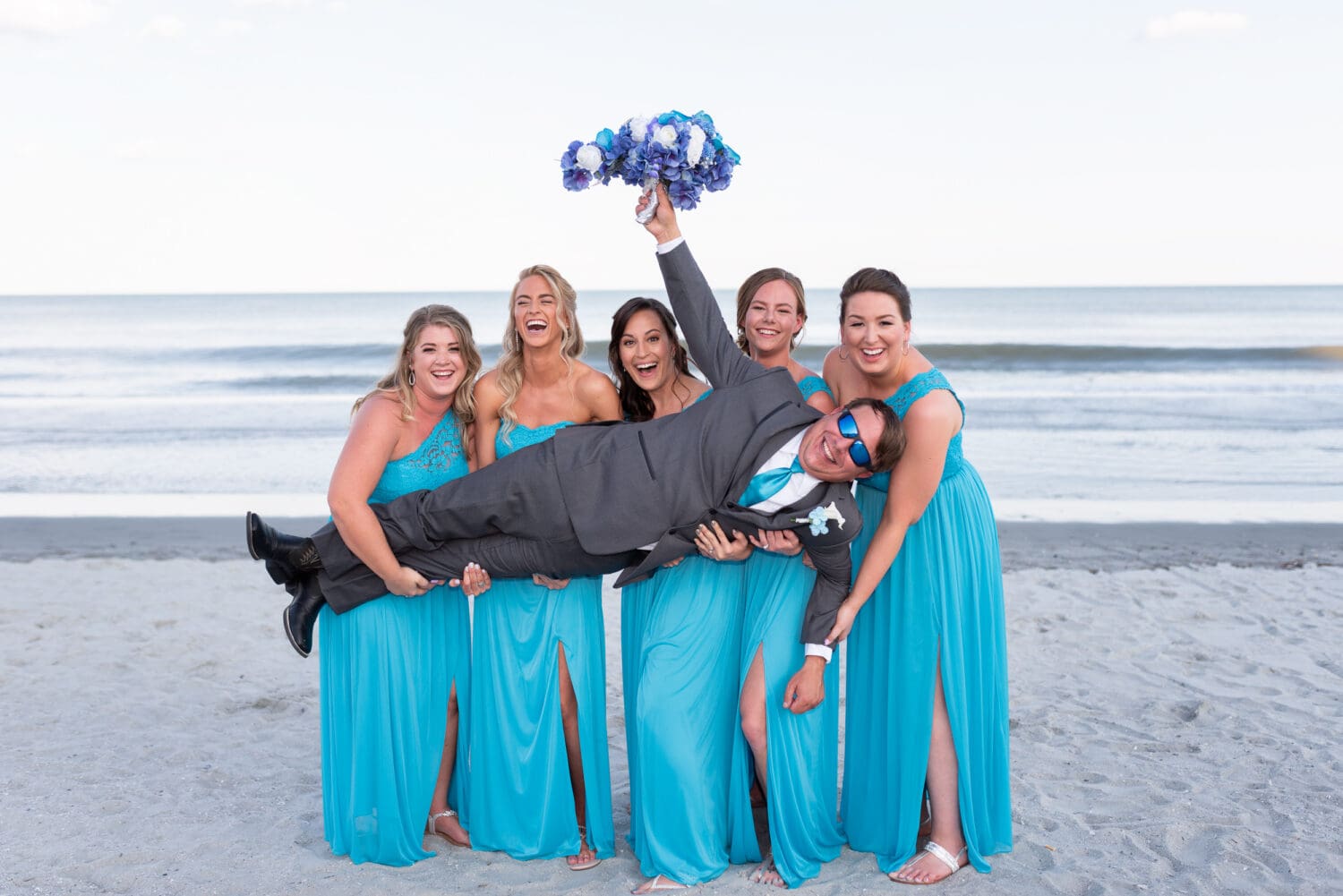 Fun picture with the bridesmaids holding up the groom by the ocean - Grande Dunes Ocean Club