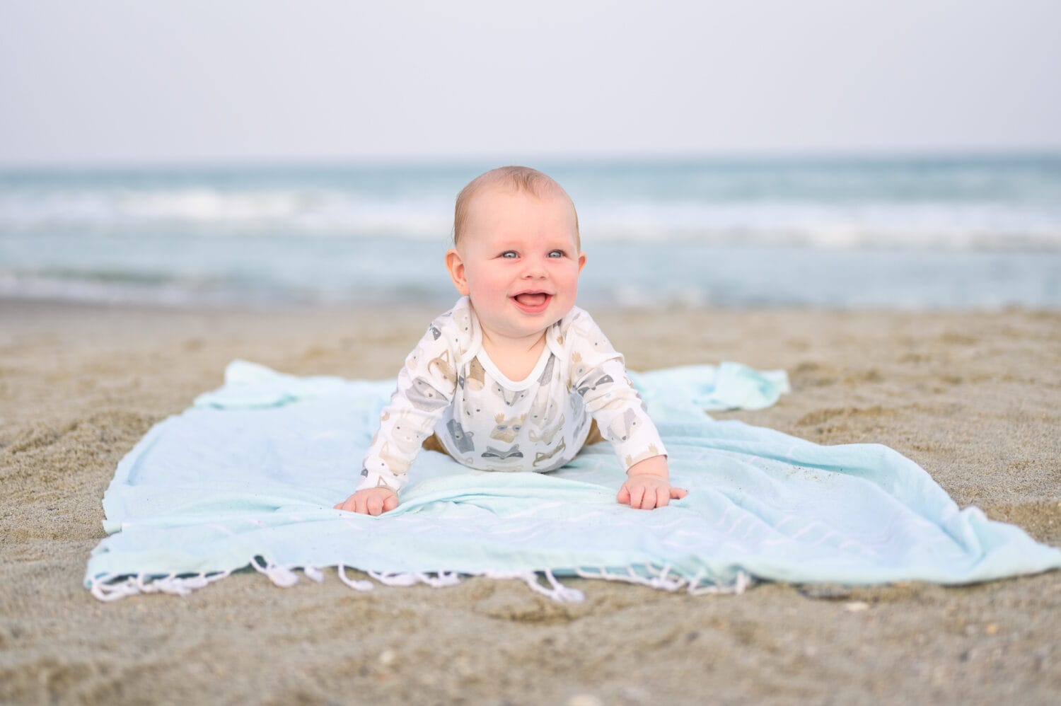 Happy baby laying on blanket by the ocean at sunset - North Myrtle Beach