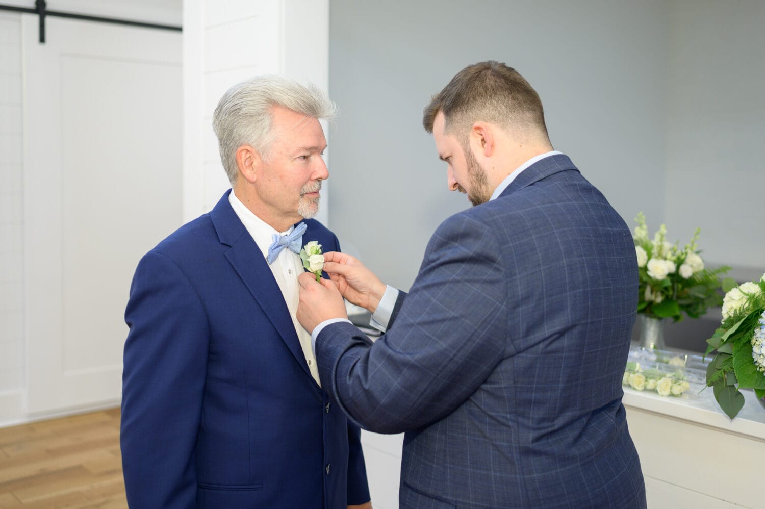 Groom helping father with boutonniere  - The Venue at White Oaks Farm