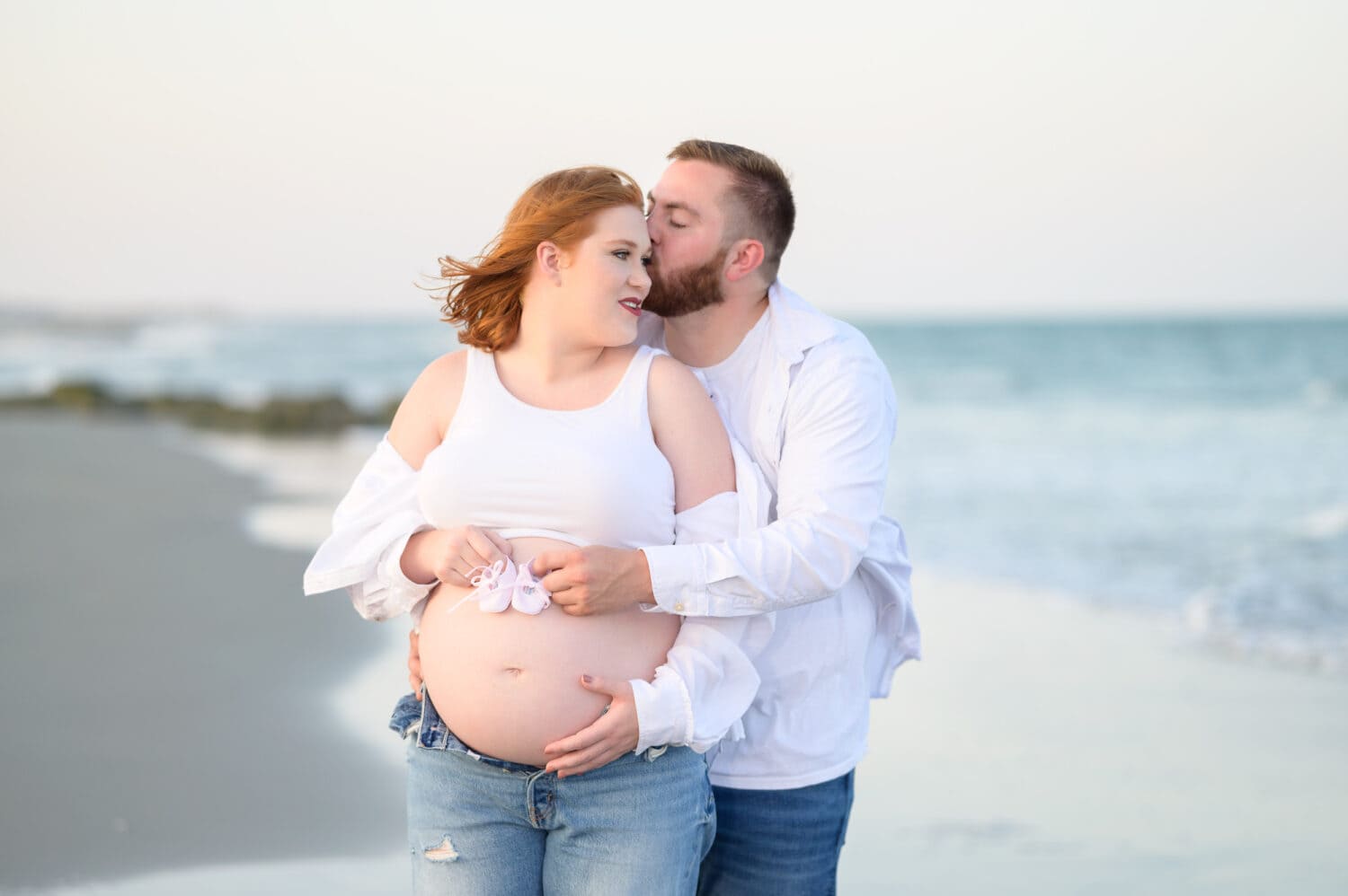 Husband and wife maternity portrait holding baby shoes over the belly - The Pelican Inn