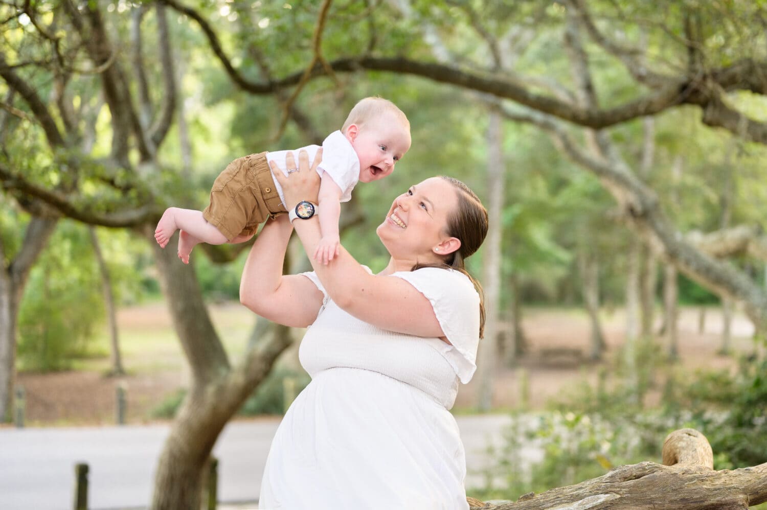 Mom holding happy baby boy in the air -