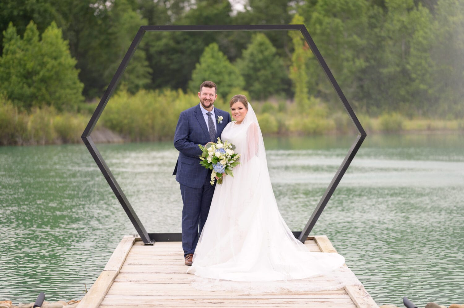 Portraits of the bride and groom in front of the hexagon on the lake - The Venue at White Oaks Farm