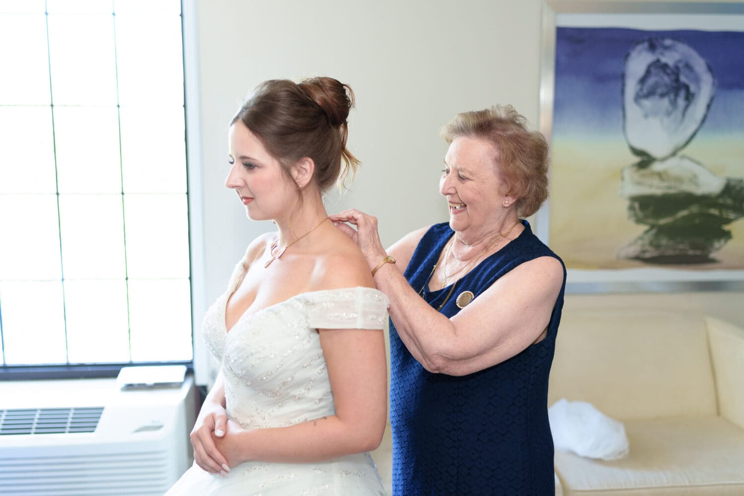 Grandmother putting on bride's necklace - Hotel Indigo