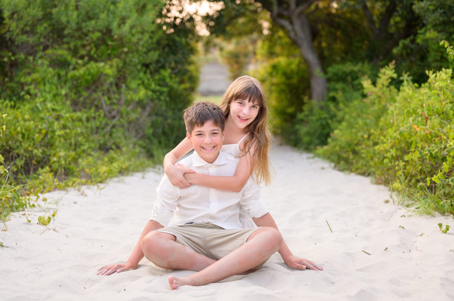 Happy little brother and sister sitting on the beach path - Huntington Beach State Park