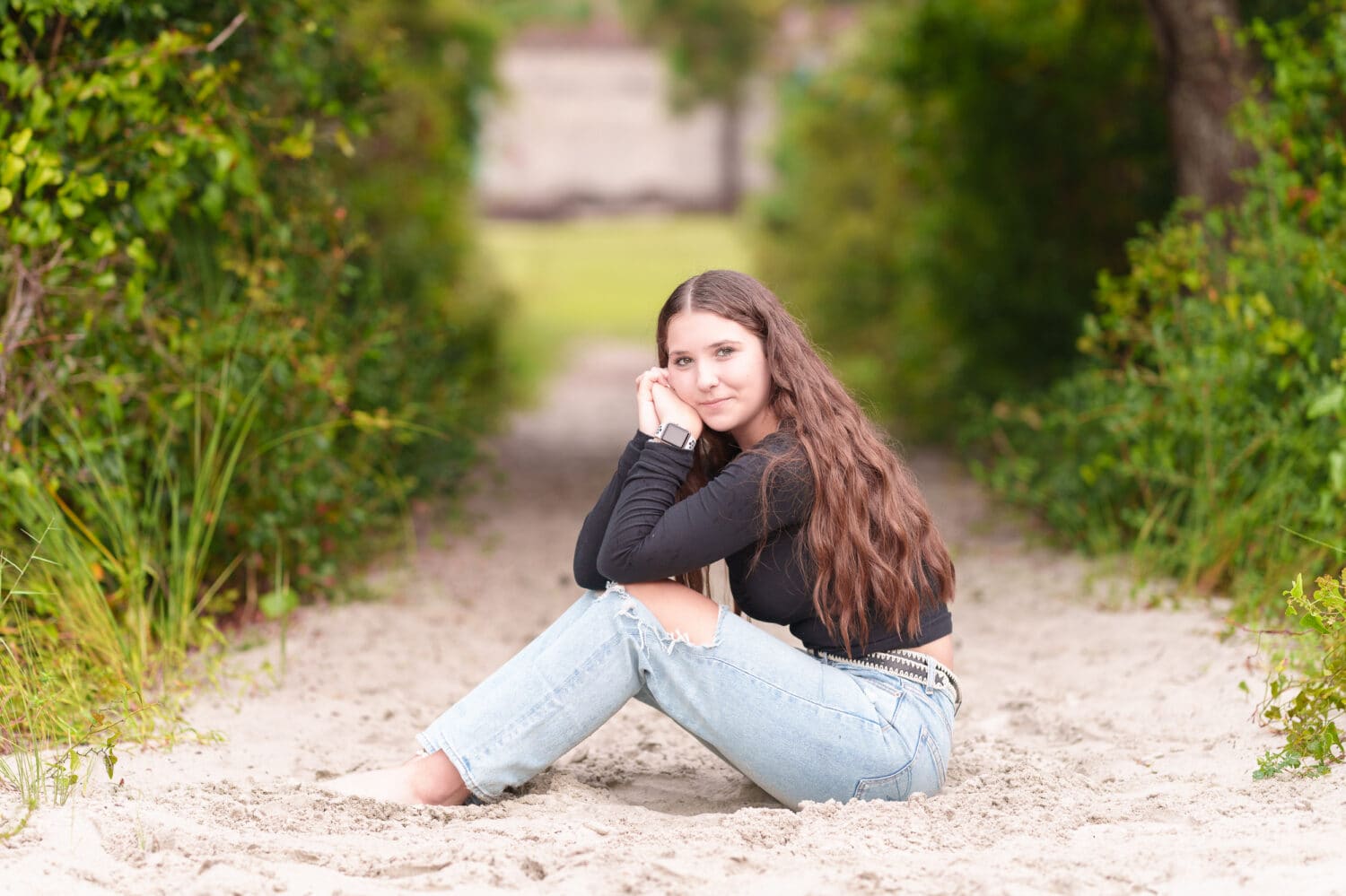 Senior girl leaning on her knees sitting in the sand - Huntington Beach State Park