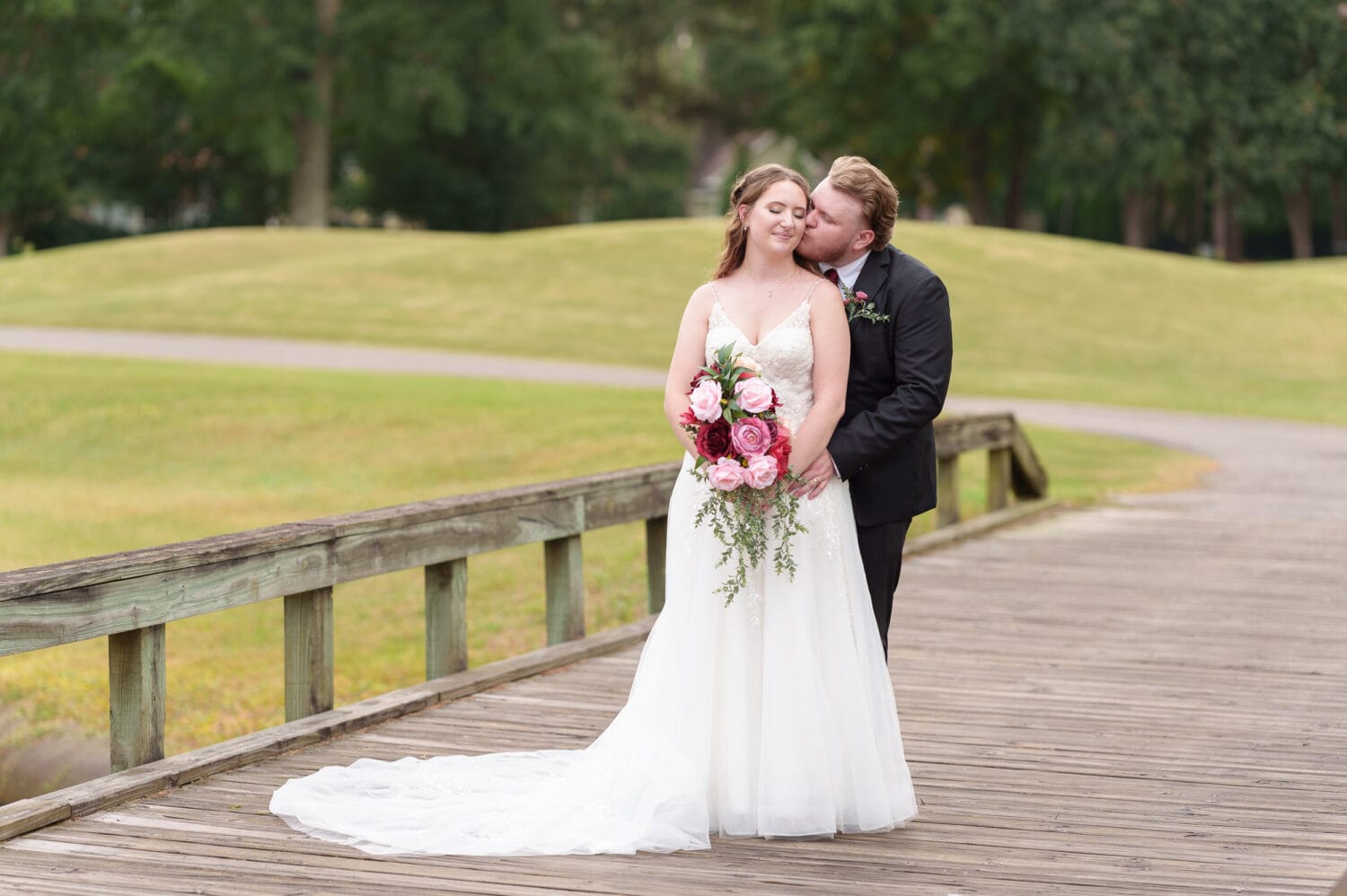 Bride and groom embracing on the golf course bridge behind the clubhouse - Litchfield Country Club