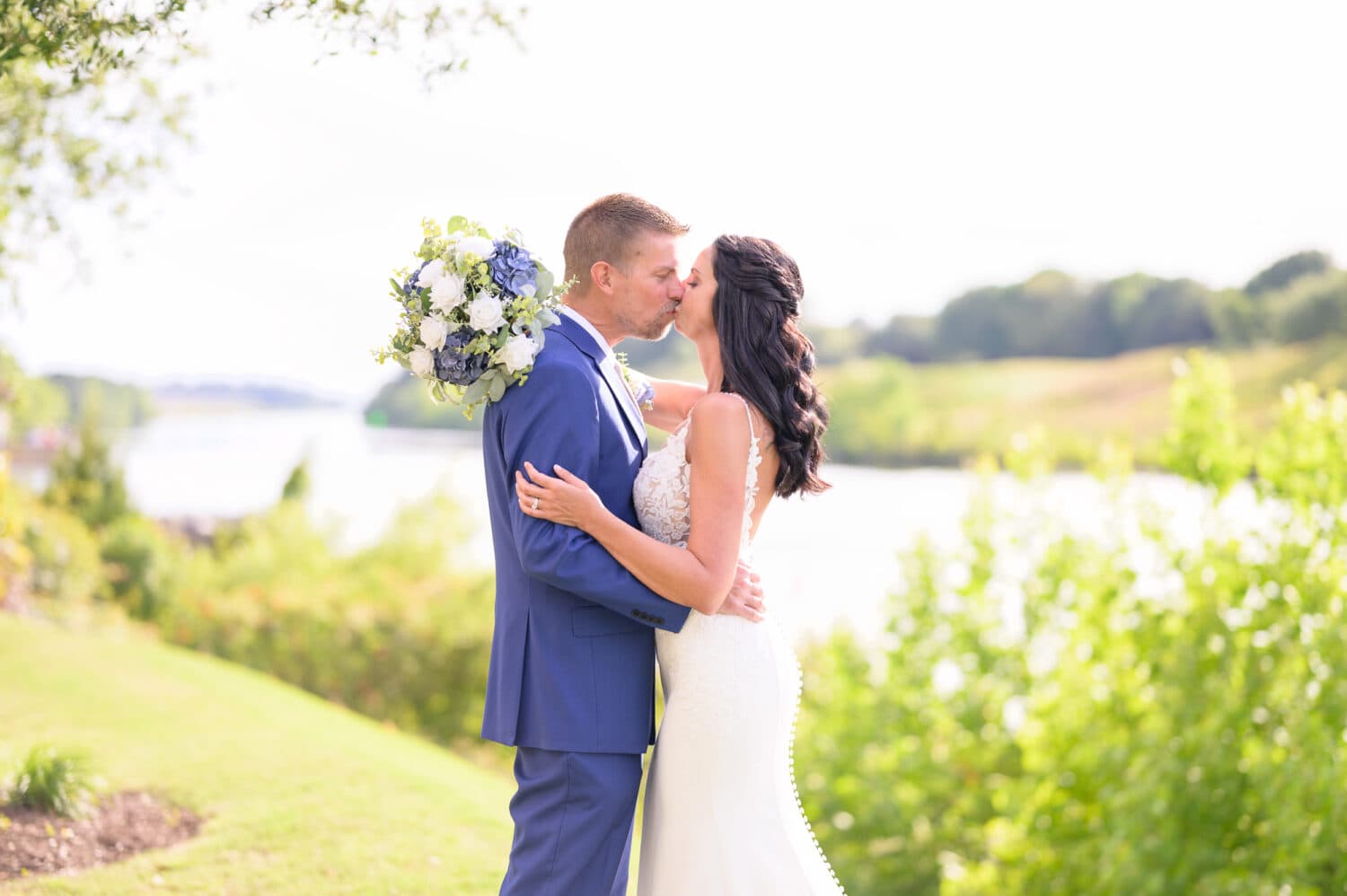 Kiss on the grassy hill by the water - The Marina Inn