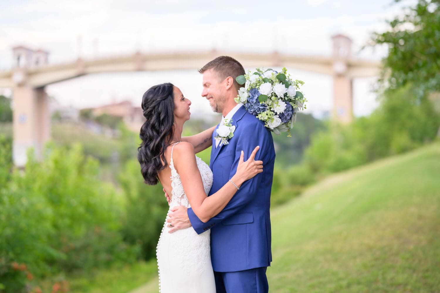 Portraits of bride and groom on the grassy hill with the Grande Dunes bridge in the background - The Marina Inn
