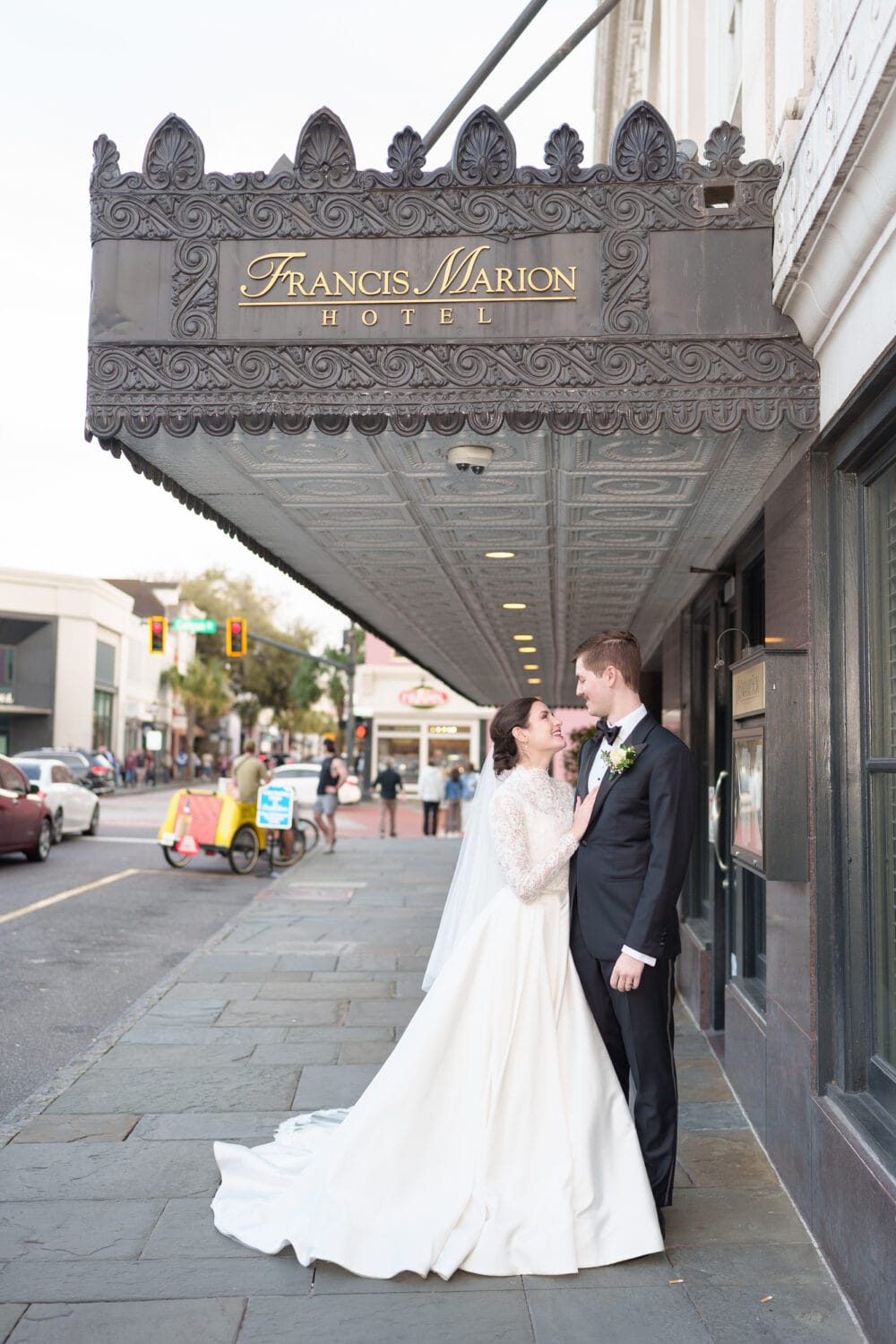Bride and groom kissing under the Francis Marion hotel awning - Francis Marion Charleston