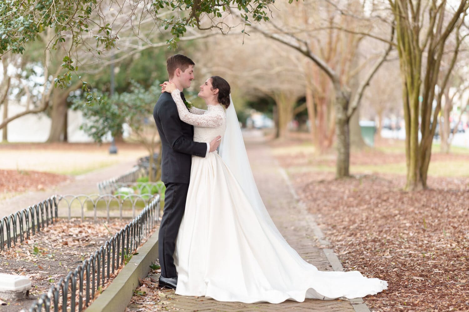 Bride and groom smiling at each other on the brick path - Marion Square Charleston