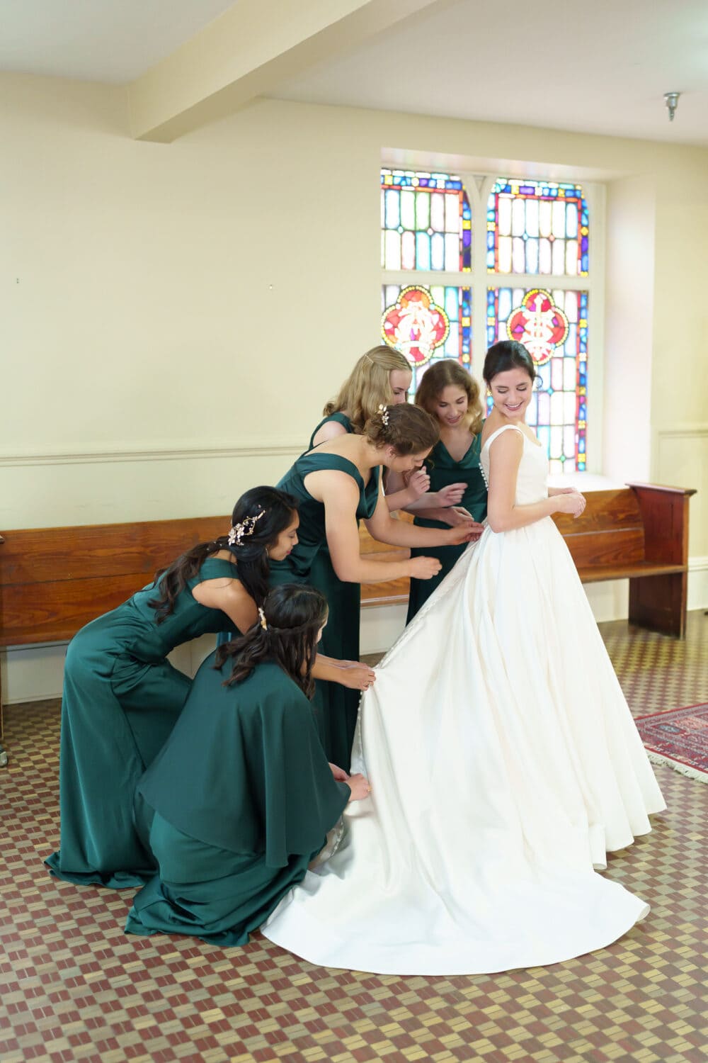 Bridesmaids helping bride with her dress - Cathedral of Saint John Charleston