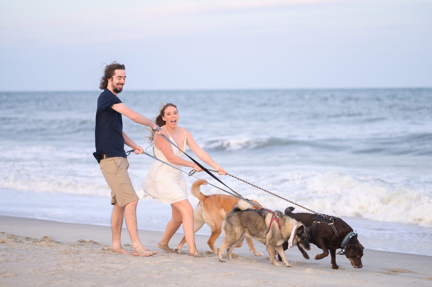 Happy couple with their three dogs for engagement pictures - Huntington Beach State Park