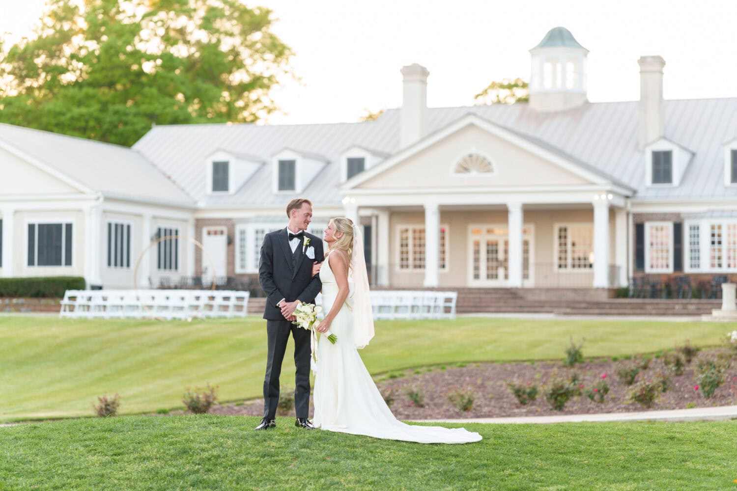 Bride and groom looking into each other's eyes with clubhouse in the background - Pawleys Plantation