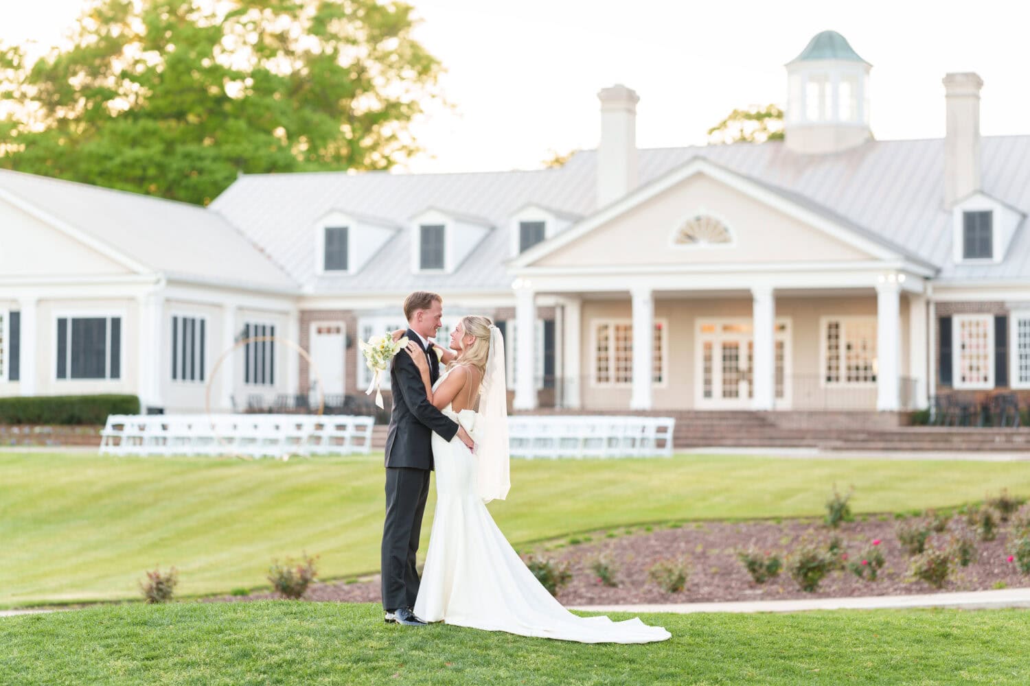 Bride and groom looking into each other's eyes with clubhouse in the background - Pawleys Plantation