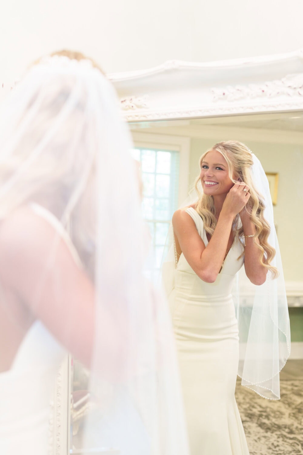 Bride putting earrings on in the mirror - Pawleys Plantation