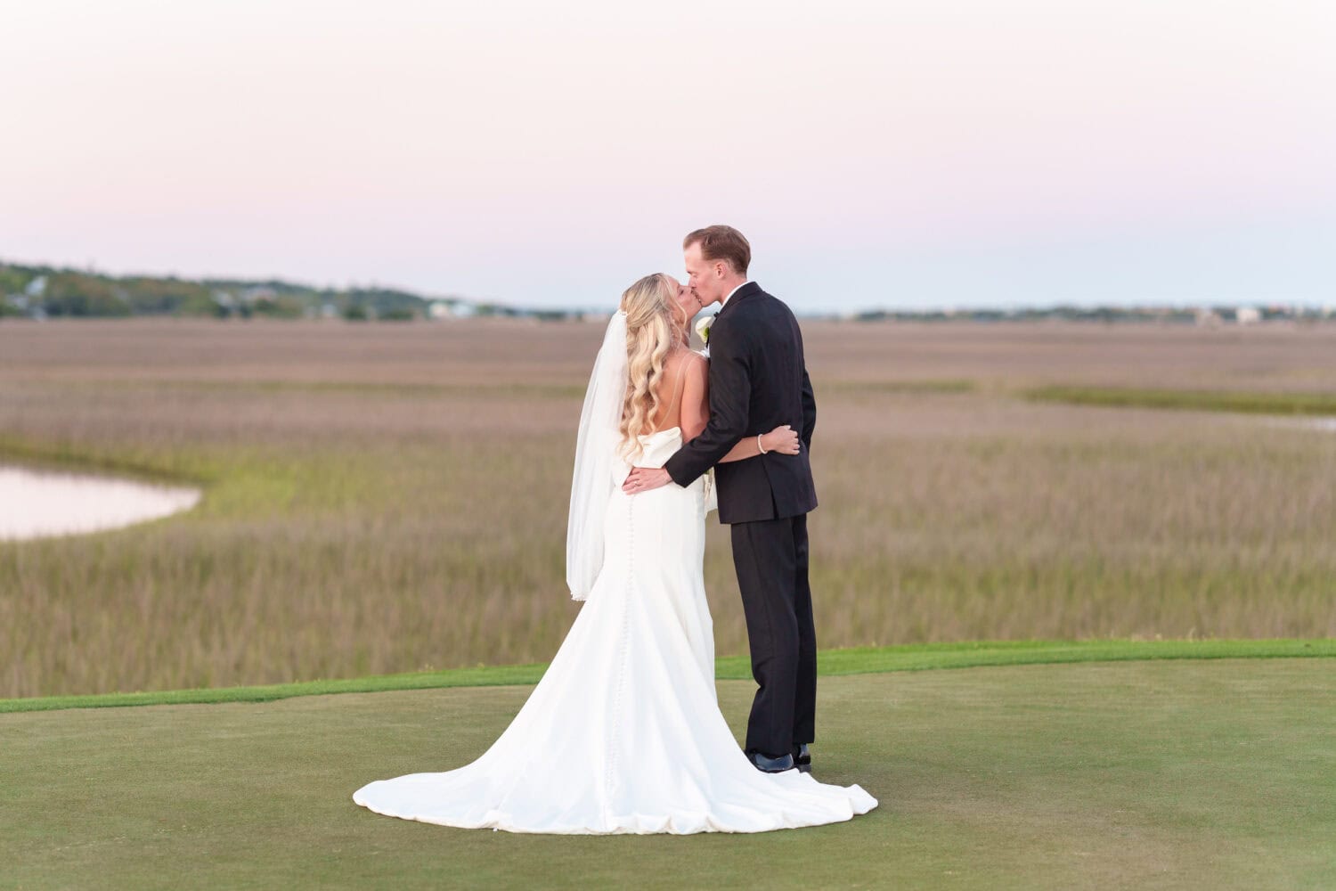 Kiss with brides dress flowing behind her - Pawleys Plantation
