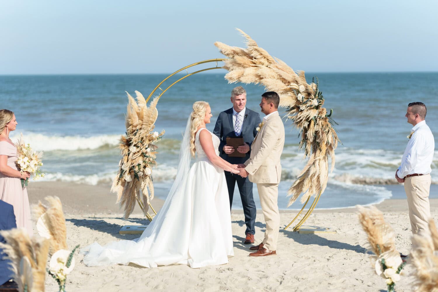 Holding hands under the wedding arch - Beach House in Pawleys Island